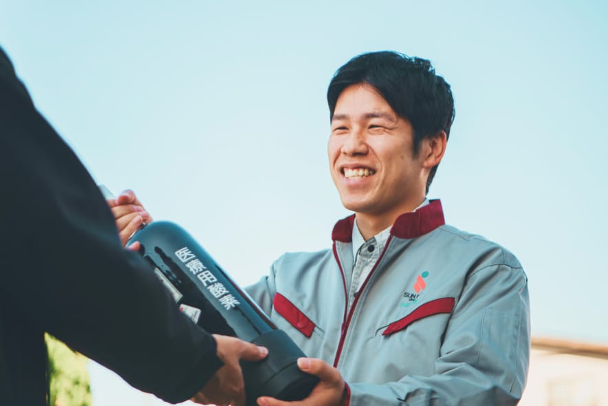 医療用ガスボンベを手渡す社員